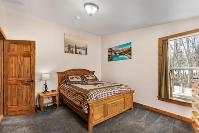 bedroom featuring baseboards and dark carpet