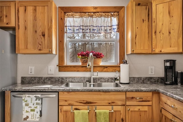 kitchen with appliances with stainless steel finishes, dark countertops, and a sink