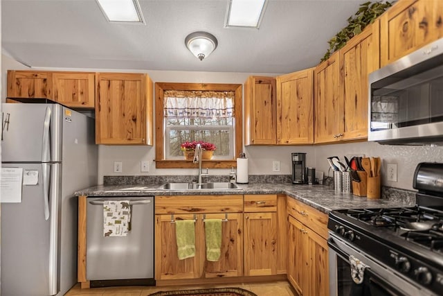 kitchen with stainless steel appliances, dark countertops, and a sink