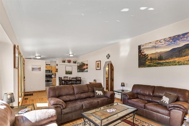 living room featuring arched walkways and light wood finished floors