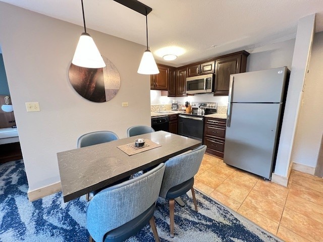 kitchen with appliances with stainless steel finishes, dark brown cabinets, light tile patterned floors, and decorative light fixtures