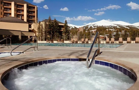 snow covered pool featuring a community hot tub and a mountain view