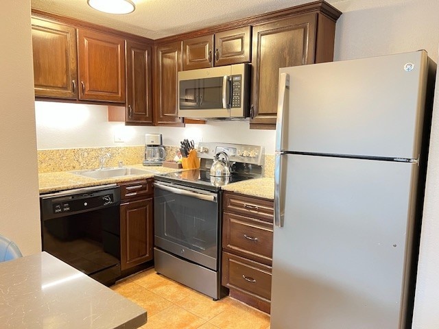 kitchen featuring stainless steel appliances, sink, a textured ceiling, and light stone counters