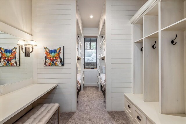 mudroom featuring light carpet and wooden walls