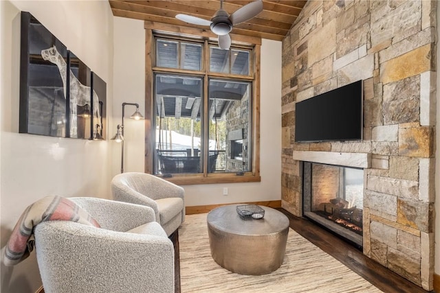 living room featuring lofted ceiling, wooden ceiling, a stone fireplace, hardwood / wood-style flooring, and ceiling fan