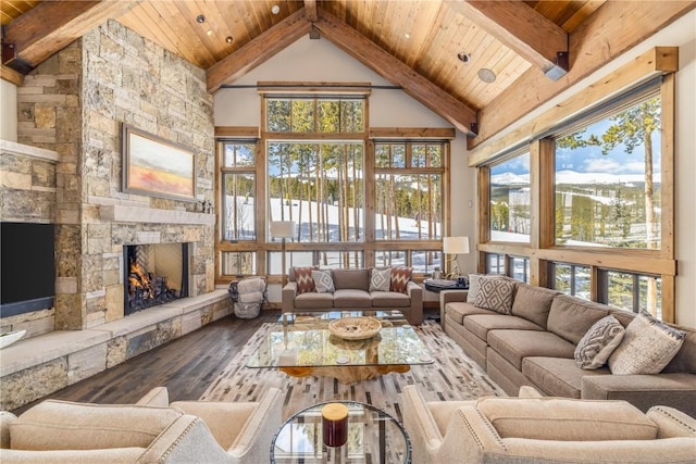 living room with beam ceiling, a stone fireplace, wooden ceiling, and wood-type flooring