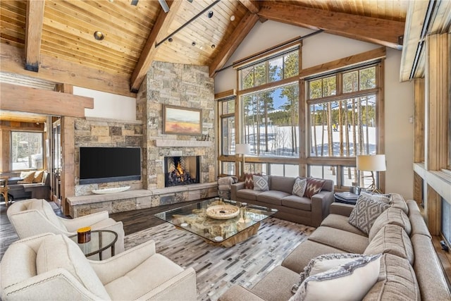 living room with beamed ceiling, light hardwood / wood-style floors, a stone fireplace, and wooden ceiling