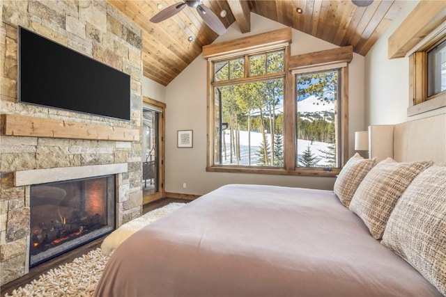 bedroom with vaulted ceiling with beams, a stone fireplace, ceiling fan, and wood ceiling