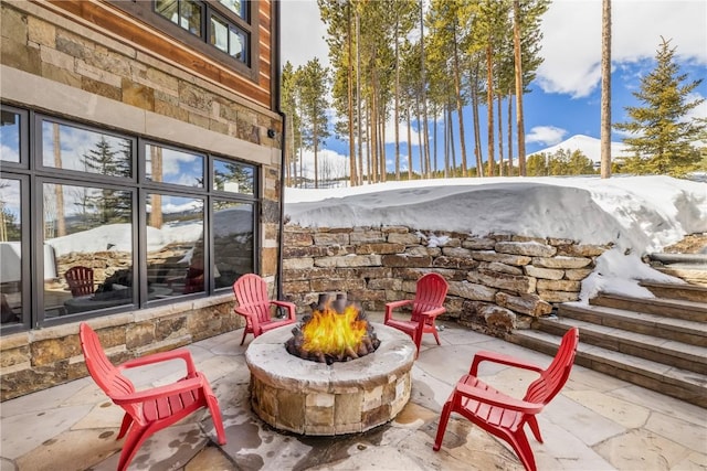 snow covered patio with an outdoor fire pit