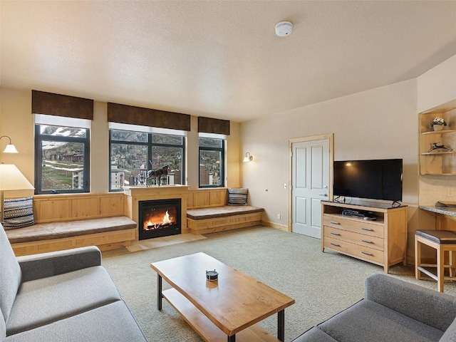 carpeted living room with baseboards, a warm lit fireplace, and a textured ceiling