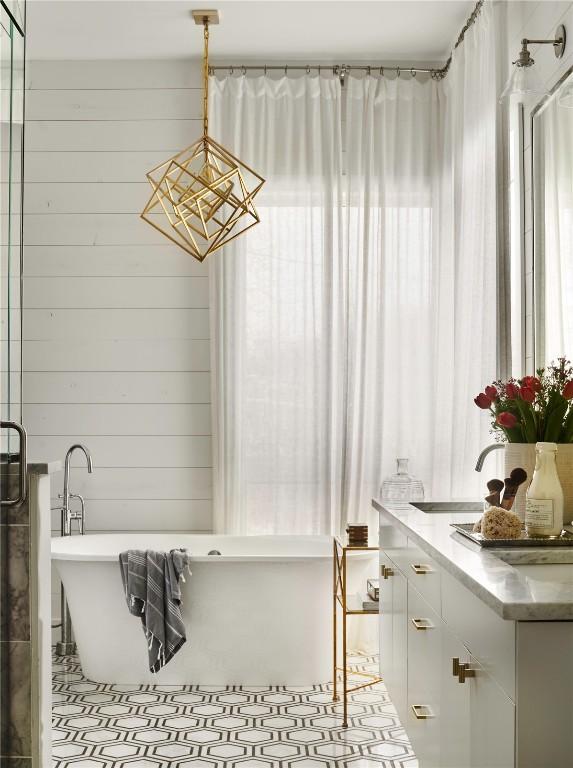 full bath featuring a soaking tub, vanity, and wooden walls