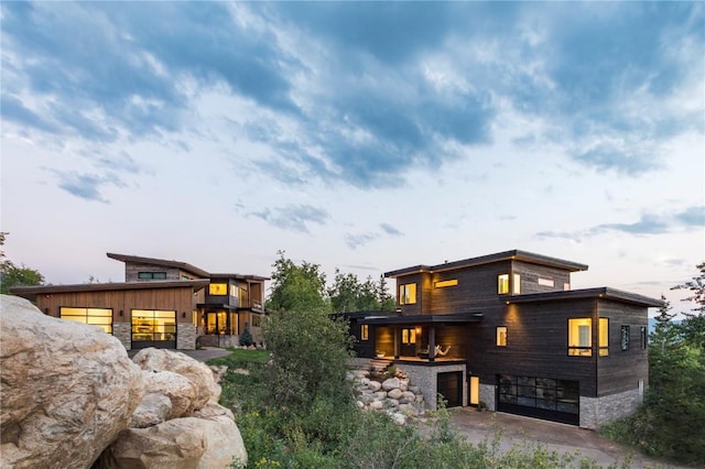 back of house with a garage and stone siding