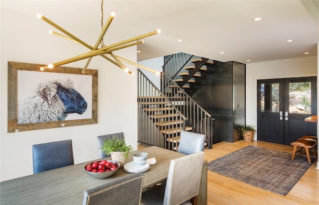 dining space with french doors, light hardwood / wood-style floors, and a notable chandelier