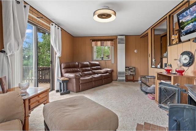 living room with wooden walls, a healthy amount of sunlight, and light carpet