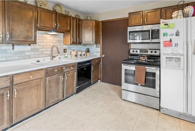 kitchen with sink, light tile patterned flooring, backsplash, and appliances with stainless steel finishes