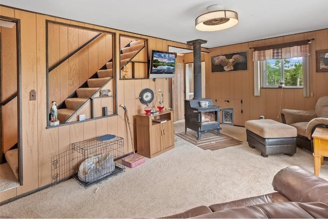 living room with wooden walls, light carpet, and a wood stove