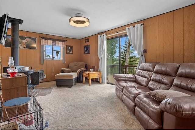 carpeted living room with wood walls and a wood stove