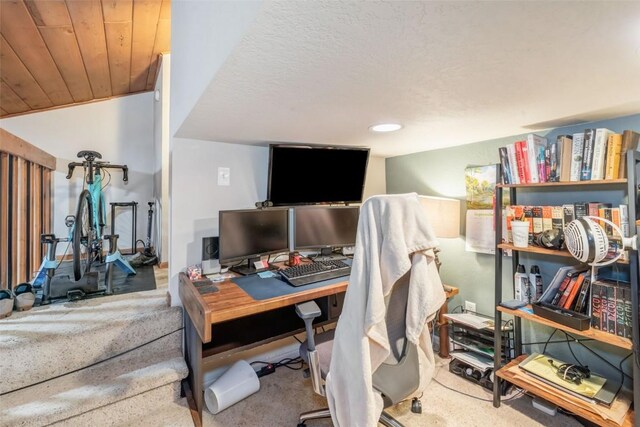 carpeted home office with wood ceiling