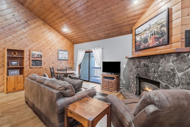 living room featuring wooden walls, light wood-type flooring, lofted ceiling, a stone fireplace, and wooden ceiling