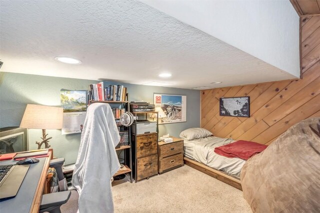 carpeted bedroom with a textured ceiling and wooden walls