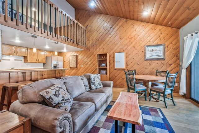 living room featuring wood walls, light hardwood / wood-style flooring, high vaulted ceiling, and wooden ceiling