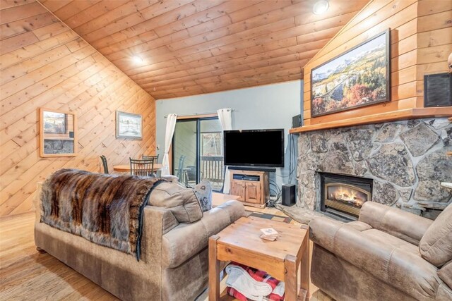 living room featuring wood walls, wooden ceiling, vaulted ceiling, light hardwood / wood-style flooring, and a fireplace