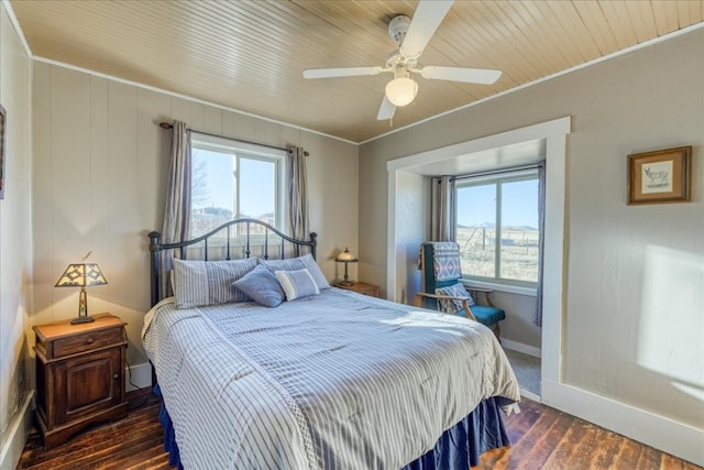 bedroom featuring dark wood-style floors, crown molding, baseboards, and a ceiling fan