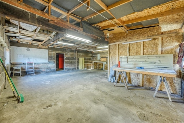 misc room featuring a garage, a workshop area, and unfinished concrete flooring