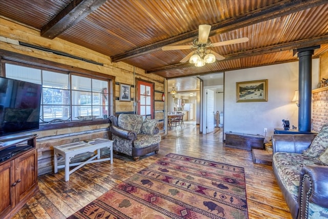 living area featuring wood ceiling, beam ceiling, hardwood / wood-style flooring, and a wood stove