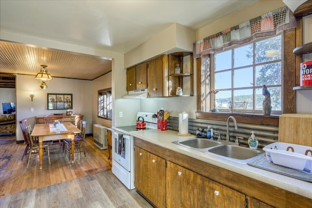 kitchen with white electric stove, brown cabinets, range hood, open shelves, and a sink