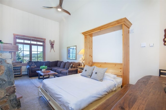 bedroom featuring ceiling fan, a high ceiling, baseboard heating, and carpet