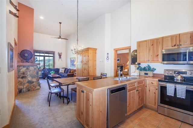 kitchen featuring appliances with stainless steel finishes, sink, a chandelier, hanging light fixtures, and kitchen peninsula