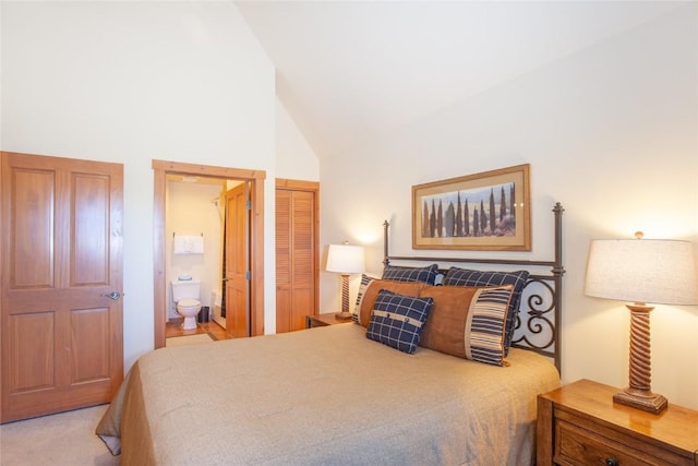 bedroom with connected bathroom and high vaulted ceiling