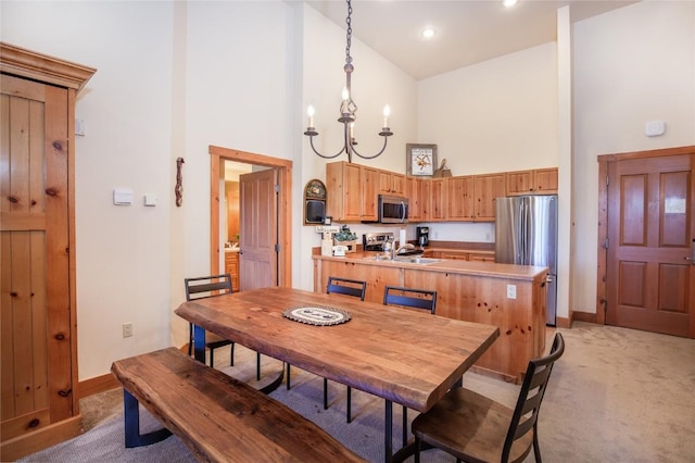 dining room with an inviting chandelier, sink, high vaulted ceiling, and light carpet