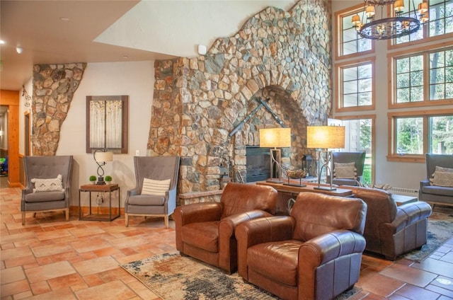 interior space featuring a high ceiling, a stone fireplace, and an inviting chandelier