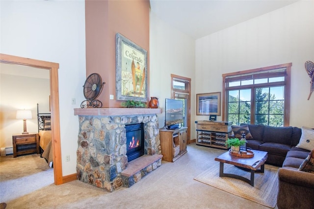 carpeted living room featuring a high ceiling and a stone fireplace