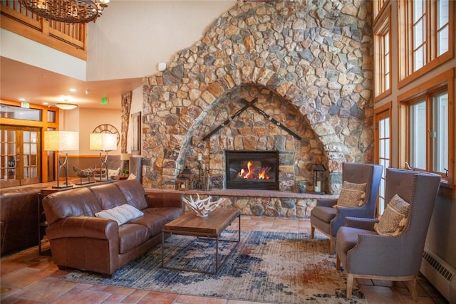 living room with a baseboard heating unit, a fireplace, and a towering ceiling