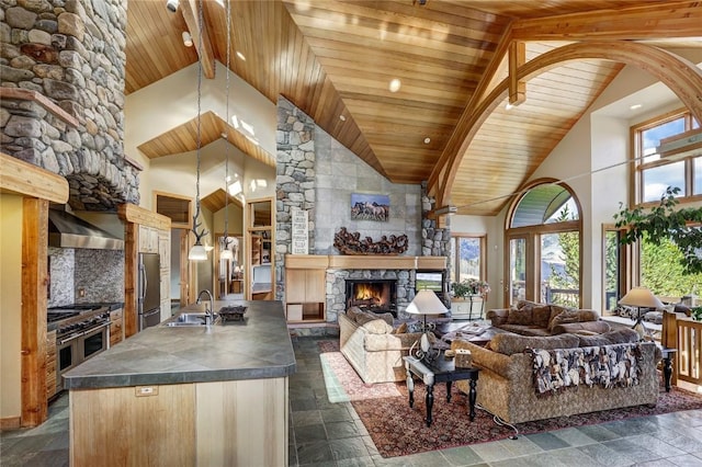 living room with beamed ceiling, sink, a fireplace, and high vaulted ceiling