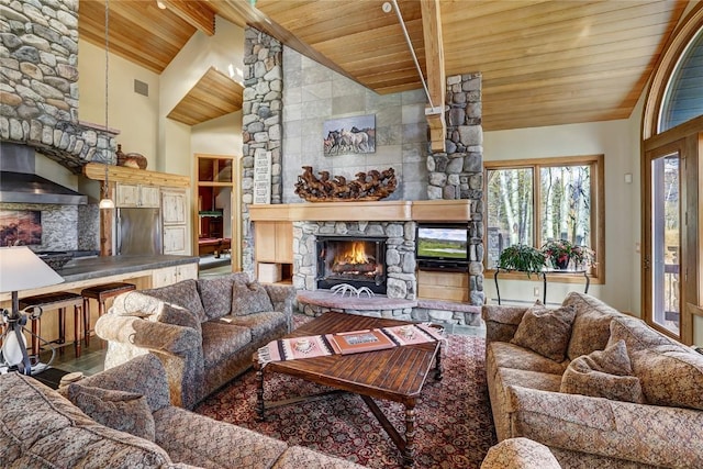 living room with beamed ceiling, high vaulted ceiling, a stone fireplace, and wood ceiling