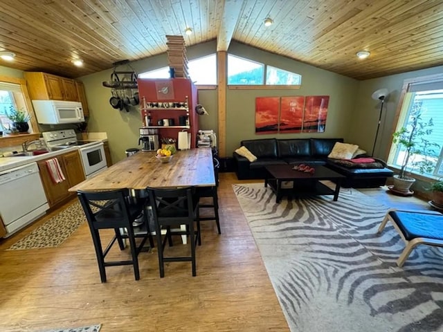 interior space with white appliances, plenty of natural light, lofted ceiling with beams, light countertops, and light wood-style floors