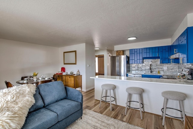 kitchen with appliances with stainless steel finishes, blue cabinetry, sink, and kitchen peninsula