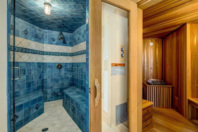 bathroom with a shower with shower door, wood walls, and wooden ceiling