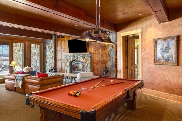 rec room featuring beamed ceiling, carpet, and a stone fireplace