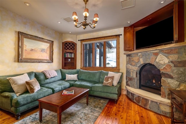 living room with a notable chandelier, hardwood / wood-style flooring, and a fireplace