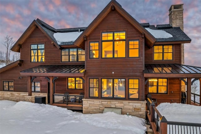 snow covered rear of property with covered porch