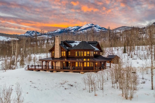 snow covered back of property featuring a mountain view