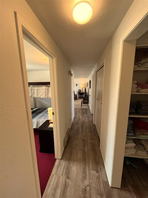 hallway with dark wood-style floors, baseboards, and a textured ceiling