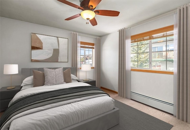 carpeted bedroom with a baseboard heating unit and a ceiling fan