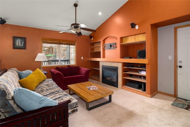 carpeted living area with ceiling fan, baseboards, built in features, a tile fireplace, and high vaulted ceiling