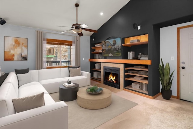 carpeted living room with high vaulted ceiling, built in features, baseboards, ceiling fan, and a tile fireplace